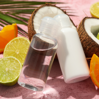 Coconut, fruits and cosmetics on pink background, close up