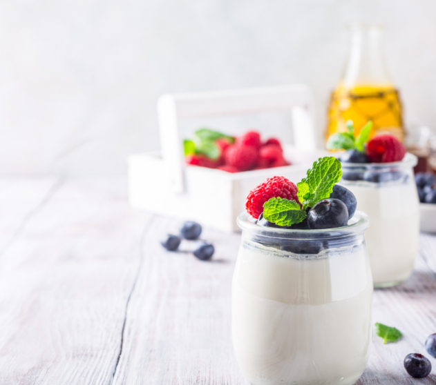Natural yoghurt with berries on light gray background. Copy space. Healthy breakfast concept.